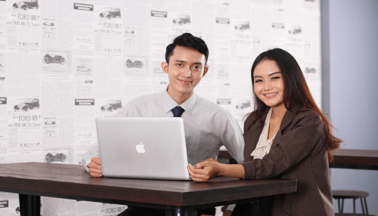 Dua mahasiswa berdiskusi tentang teknologi informasi di depan laptop